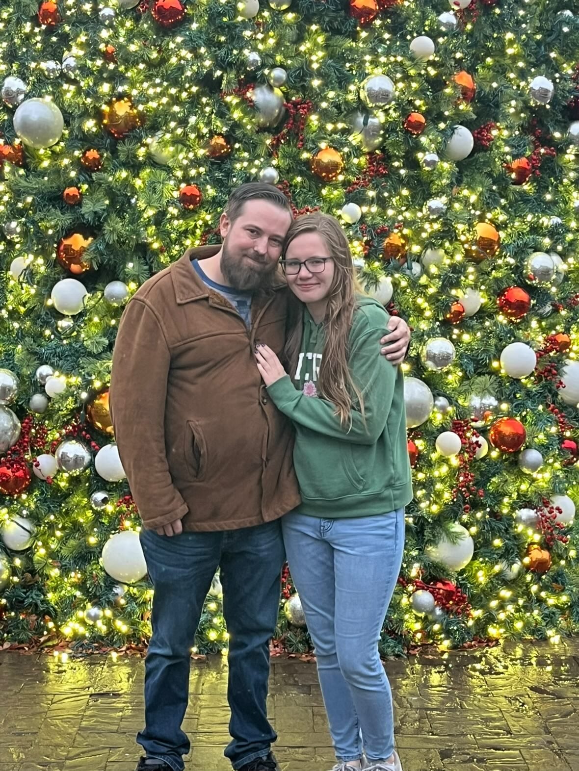 Nick and Libby standing together in front of a Christmas tree with lights and ornaments
