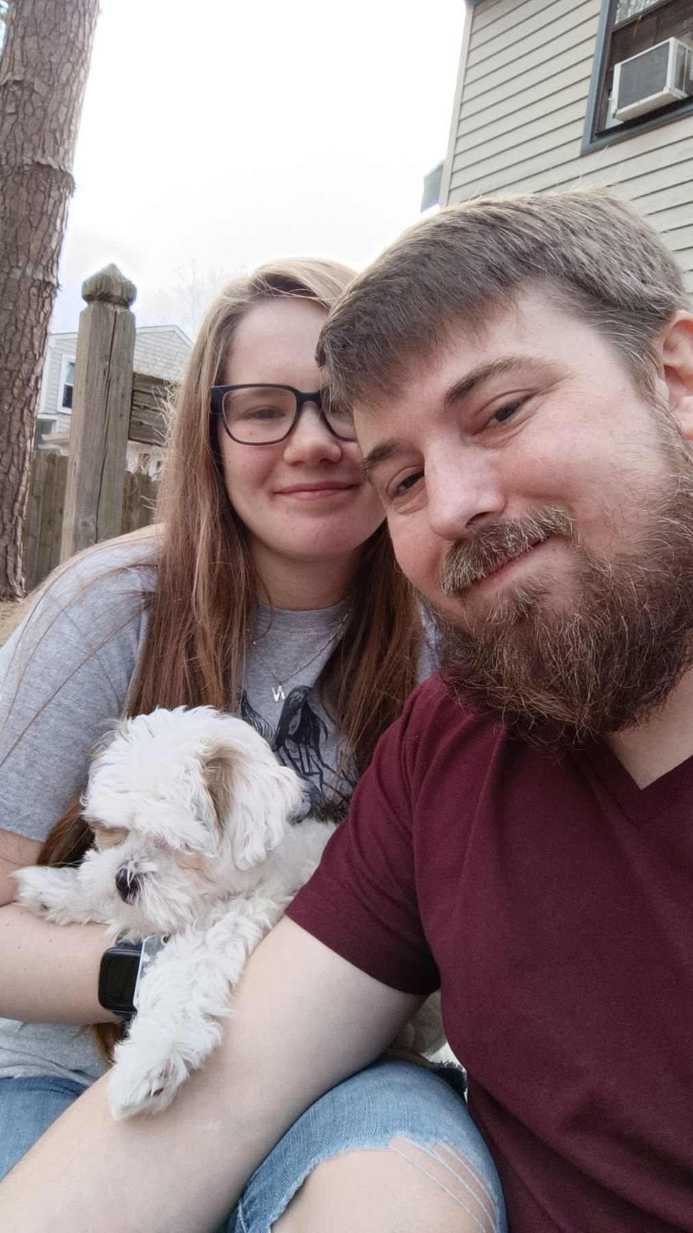 Nick and Libby taking a selfie outdoors with their small white dog