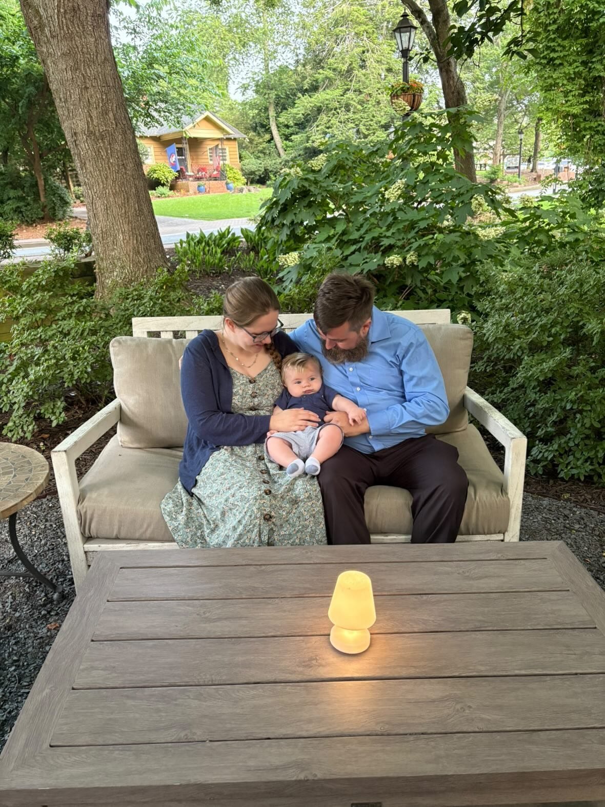 Nick and Libby sitting with their baby on an outdoor couch